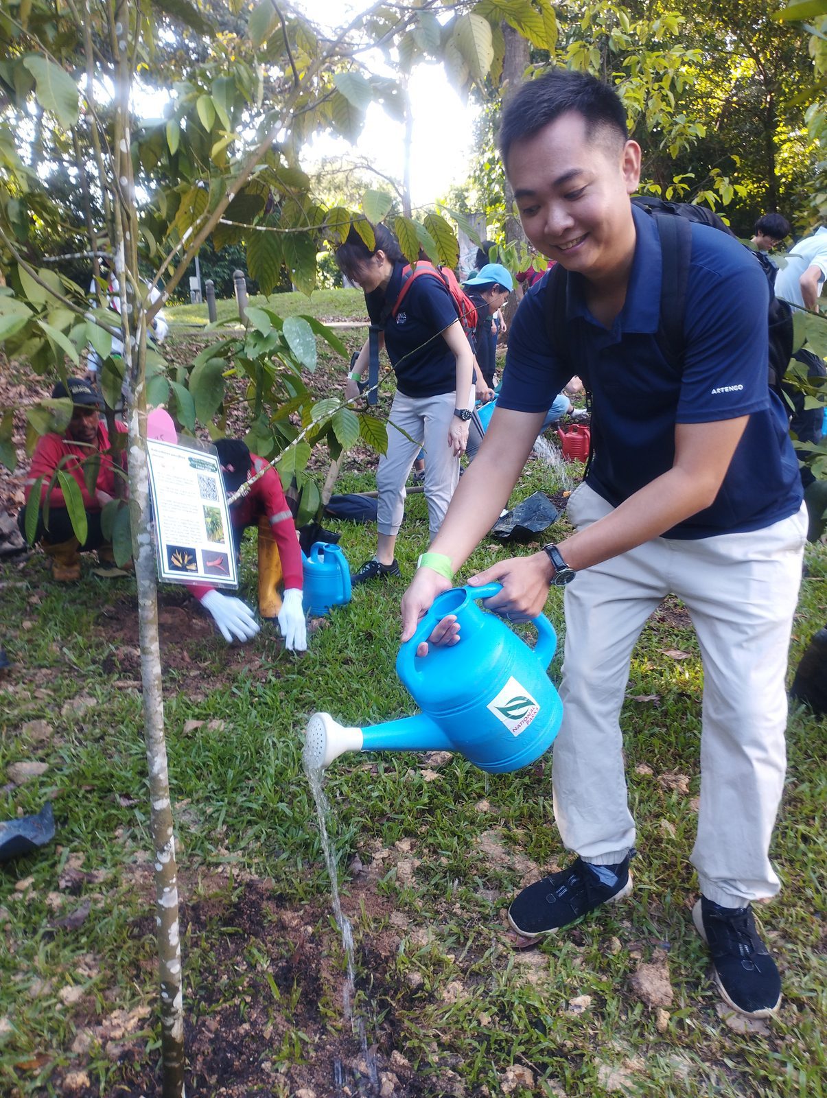 Watering a newly planted sapling at NUS